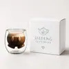 Transparent double wall coffee cup filled with coffee highlighting the playful face shaped inner design
