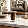 Compact 90ml double wall coffee glass with dark espresso and crema displayed inside the hourglass shaped inner chamber
