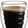 Transparent double wall coffee glass with multiple rounded horizontal wave contours inside the drinking chamber