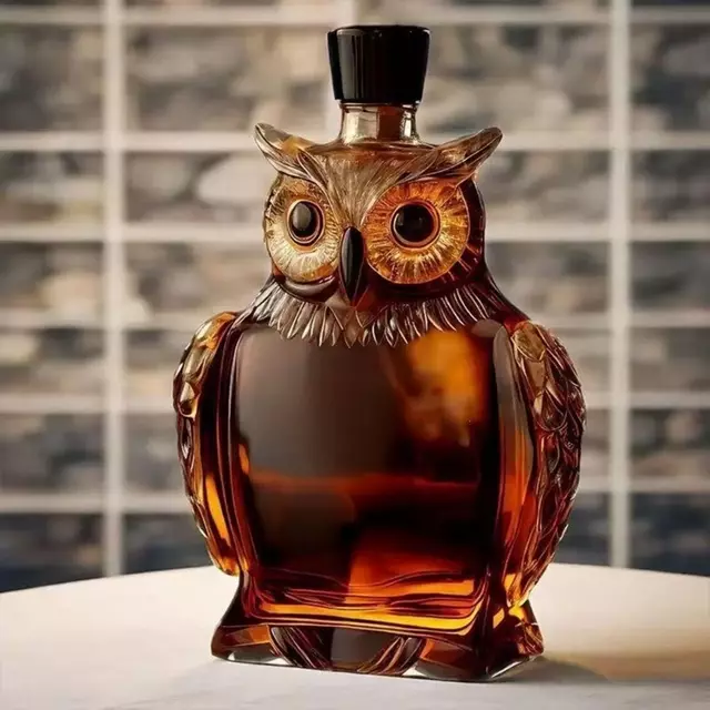 Decorative owl-shaped glass decanter filled with amber whiskey