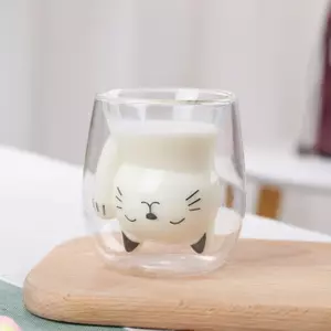 transparent double wall glass cup with cute cat face design filled with milk