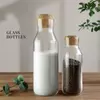 Transparent glass bottles with natural cork stoppers, airtight and leakproof design, perfect for storing milk, juice, dry fruits, or grains in the kitchen
