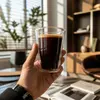 Modern transparent double wall coffee cup filled with dark coffee and golden crema