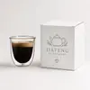 Rounded transparent double wall drinking cup displaying coffee inside a separate inner glass chamber
