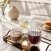 Transparent rounded drinking glass featuring decorative vertical fluted lines