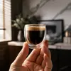 Transparent double wall espresso glass filled with dark coffee and golden crema