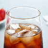 Tall tapered drinking glass filled with iced black coffee and ice cubes