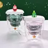 Jiateng glass mug with swirling snow-core and Christmas tree lid, perfect for eggnog.