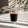 Modern transparent double wall coffee glass filled with dark coffee and a golden crema layer