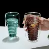 Spiral double wall glass cup filled with latte on table