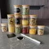 Set of clear glass storage jars with natural bamboo lids and black chalkboard labels for pantry organization.