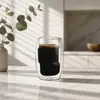 Rounded transparent double wall coffee glass filled with dark coffee and a golden crema layer