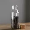 Transparent cylindrical glass bottles with cork seals, containing white liquid and black seeds, showcasing a natural, healthy, and organic lifestyle aesthetic