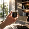 Transparent double wall coffee cup filled with black coffee and a light brown crema layer