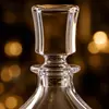 Clear whiskey decanter featuring a substantial transparent base and curved body
