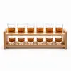 Twelve clear whiskey shot glasses displayed on a two-tier wooden rack