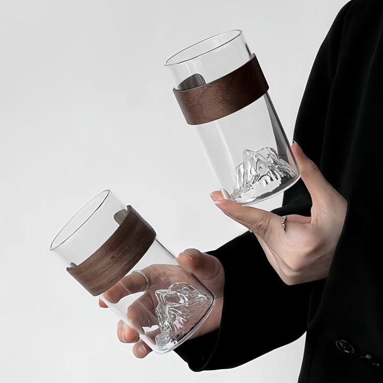Clear glass cup with realistic mountain-shaped bottom and ergonomic wooden sleeve, perfect for stylish home or office use