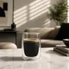 Modern transparent double wall coffee cup displaying black coffee and crema inside a rounded inner chamber